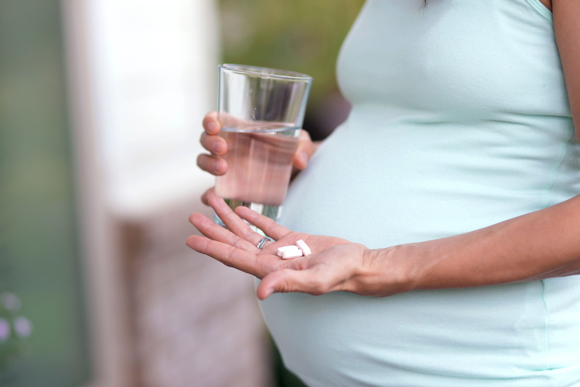 Adult pregnant woman about to swallow vitamins with water